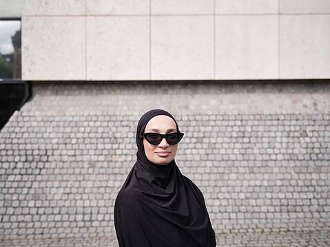 Bild von Lexware: Frau mit schwarzem Kopftuch und Sonnenbrille schaut lächelnd in die Kamera